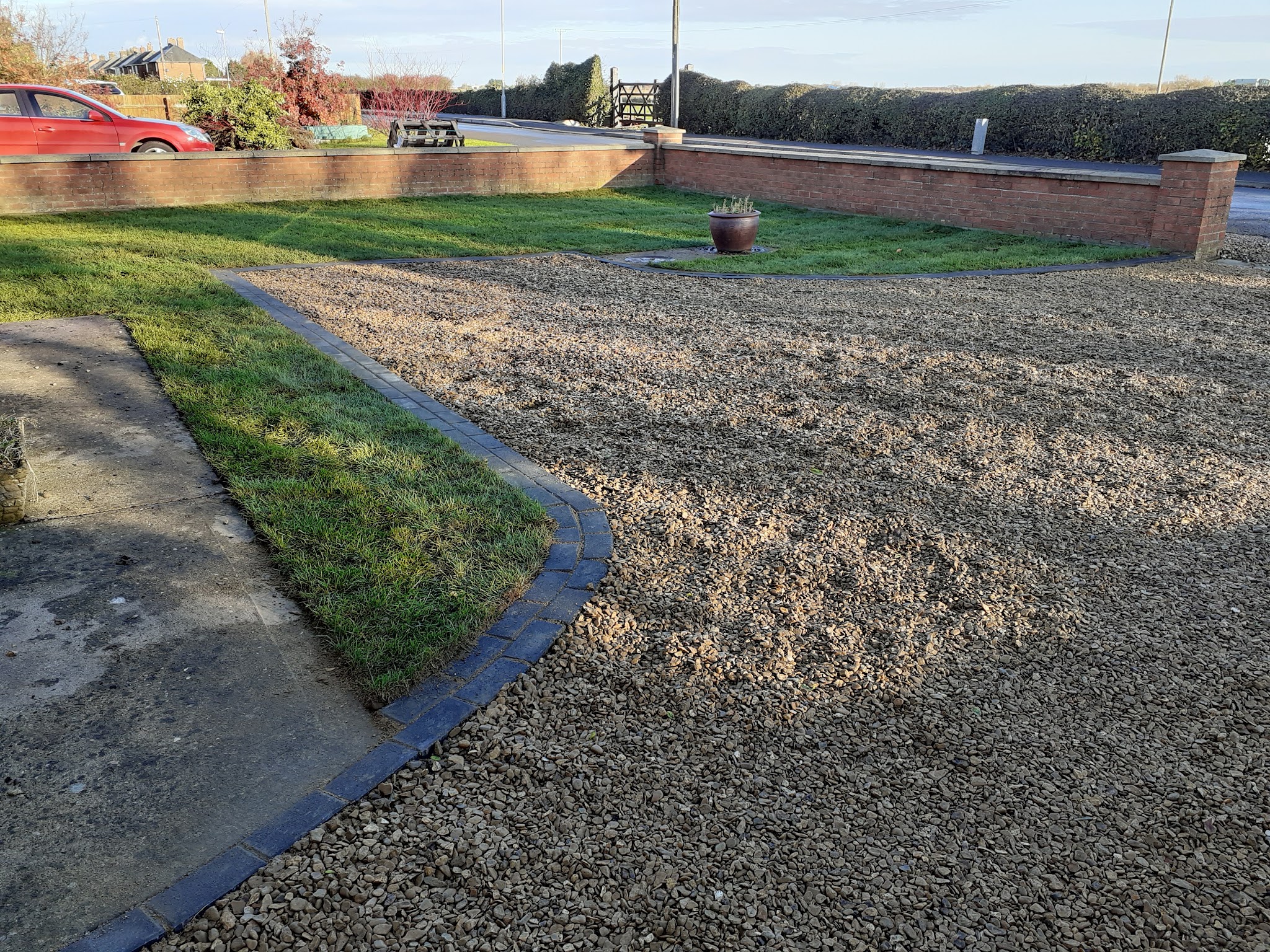 A new gravel driveway edged with lawn and dark block edging