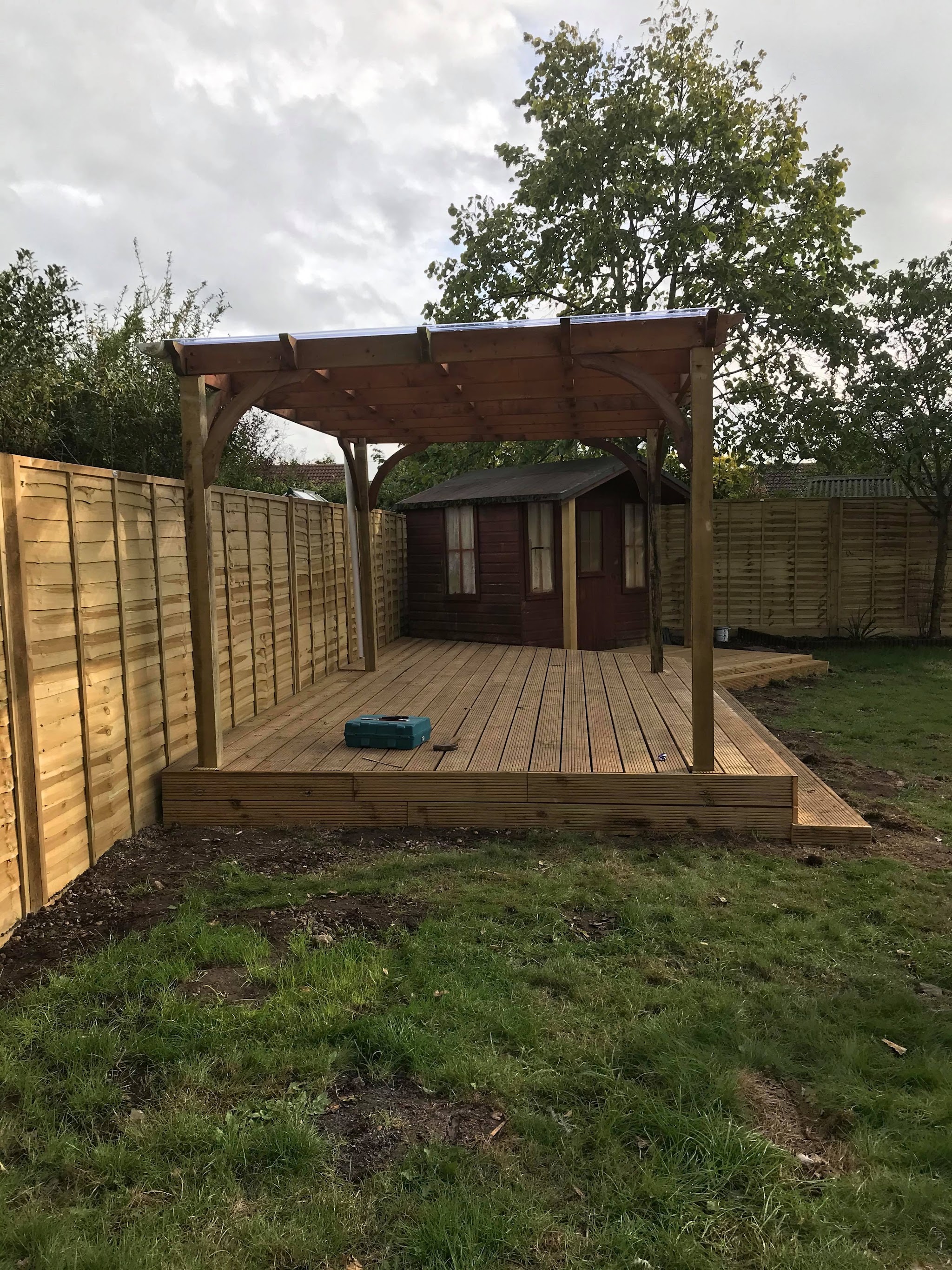 A timber pergola built over new decking, framed by fresh fence panels